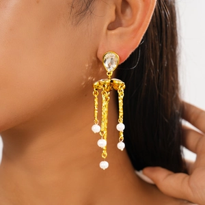 Detailed close-up of golden tassel earrings with sparkling crystals and white pearls
