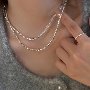 Ensemble collier et bague en perles d'argent minimaliste porté par un mannequin