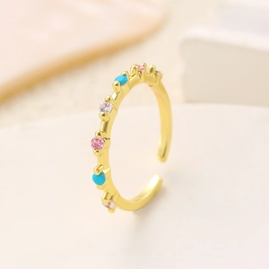 Macro detail of gold adjustable ring featuring colorful pink, white, and blue gemstones