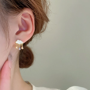 Detail of cloud-shaped shell earrings with gold plating and cubic zirconia droplets