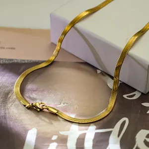 Flat gold herringbone snake chain necklace with lobster clasp on luxury fashion magazine