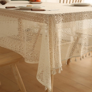 Detailed view of cream white lace tablecloth with hollow crochet patterns and fringe edges