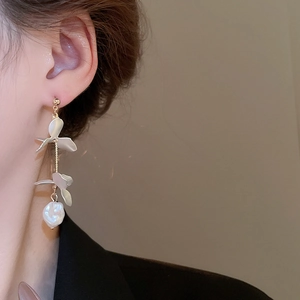 Close-up of elegant gold flower tassel earrings with white pearls worn by a model