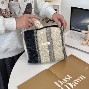 Detail van gestreepte teddy fleece make-uptas met ritssluiting en Seeakka-logo