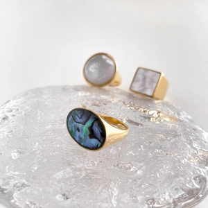 Macro shot of gold geometric rings featuring inlaid iridescent abalone and white pearl