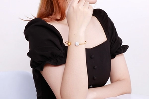 Détail du bracelet jonc doré en C avec une sphère polie et une boule sertie de cristaux