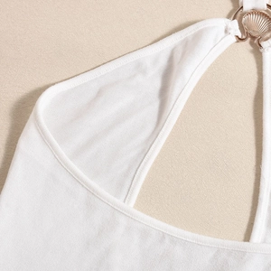 Close-up of white knit dress featuring a gold shell-shaped metal connector at the neckline