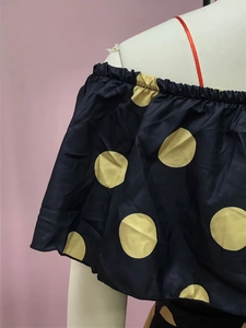 Detail eines marineblauen Off-Shoulder-Kleids mit gelben Punkten und Rüschenausschnitt