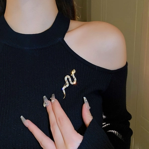 Detailed view of a gold-plated snake brooch with sparkling cubic zirconia on black fabric