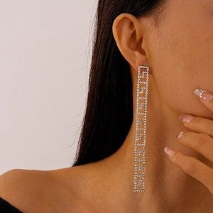 Detail of silver long dangle earrings with shimmering rhinestones and geometric Greek patterns