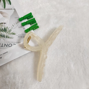 Close-up of large beige translucent jelly hair claw clip with golden metal spring detail