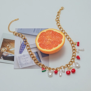 Detail of gold chunky chain necklace with cherry strawberry and pearl charms K18 mark