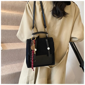 Detalle de bolso bandolera negro vintage con mezcla de cuero y colgante de borlas