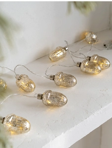 Close-up of acorn-shaped LED string lights with warm yellow glow on a textured surface