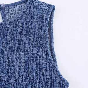 Macro detail of smocking embroidery and blue denim texture on the sleeveless dress