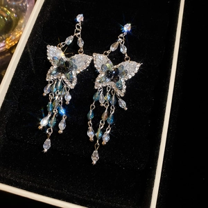 Gros plan de boucles d'oreilles papillon à pompons en cristal dans un écrin noir