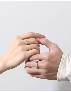 Close-up of silver S925 couple rings with minimalist twisted design and diamond accents