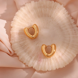 Detail of 18K gold-plated heart-shaped hoop earrings on white coral and silk fabric