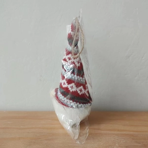 Close-up of a festive knitted Christmas gnome plush in transparent protective packaging