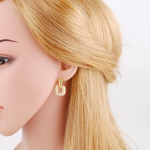 Detail view of gold U-shaped earrings with twisted metal design and zircon micro-paving