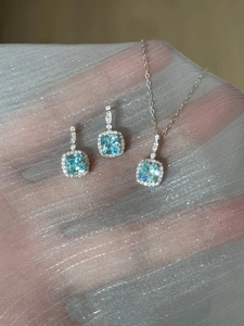 Detail of light blue square-cut gem necklace and earrings set on silver mesh fabric