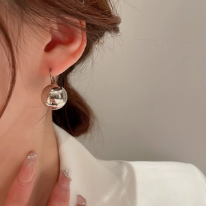 Gros plan d'une boucle d'oreille boule en argent minimaliste portée par un mannequin