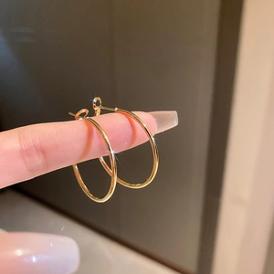 Gros plan de boucles d'oreilles créoles dorées minimalistes avec une finition polie brillante