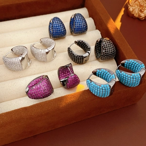 Macro shot of five pairs of C-shaped hoop earrings with colorful zircon micro-paving in a box