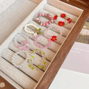 Detail of colorful handmade floral and pearl beaded stretch rings in a jewelry box