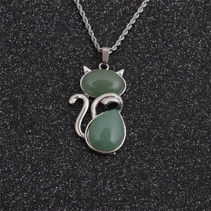 Detailed view of silver twist chain necklace with green stone cat-shaped pendant on black surface