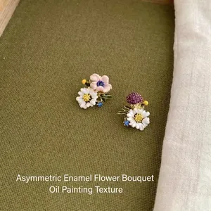 Close-up of asymmetric enamel flower bouquet earrings with colorful floral details