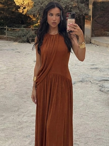 Elegant rust red halter maxi dress with pleated waist and flowing silhouette in a desert setting