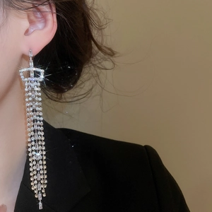 Macro detail of silver needle tassel earrings with shimmering cubic zirconia on model
