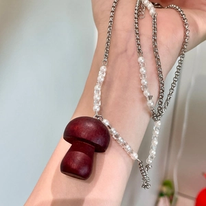 Détail du collier artisanal avec pendentif champignon en bois et perles blanches
