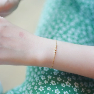 Primer plano de una pulsera de plata bañada en oro de 14k con cinco piedras de circonita