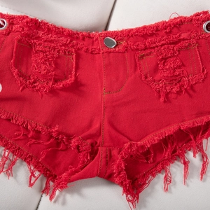 Dettaglio degli shorts in denim rosso con orli sfrangiati e bottone in metallo argento