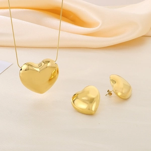 Détail d'un ensemble collier et boucles d'oreilles cœur doré sur satin beige