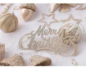 Detailed view of champagne Merry Christmas sign with gold ornaments on fake snow background