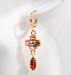 Macro shot of gold teardrop earrings with multicolor zircon floral design on white model