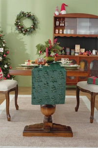 Detail of embroidered Christmas tree patterns on a deep green fabric table runner