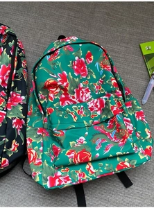 Detail of vintage floral backpacks in green and black with peony patterns and front pocket