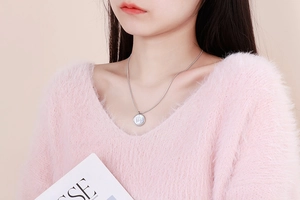 Model wearing round stainless steel necklace with pearlescent shell and zodiac sign charm