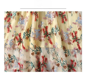 Close-up of elegant floral embroidery on light yellow tulle fabric with intricate details