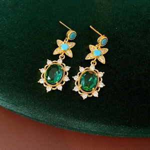 Détail de boucles d'oreilles dorées vintage avec gemme verte ovale et zircon blanc