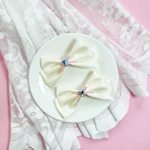 Détail de pinces à cheveux en satin crème avec strass en cœur bleu sur une assiette