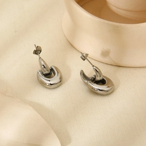 Close-up of silver minimalist drop earrings on textured beige linen background