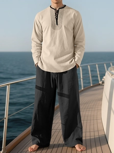 Close-up of beige linen Henley shirt and black drawstring pants on a yacht deck