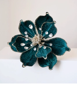 Detail of dark green velvet magnolia flower with gold glitter edges and rhinestone center