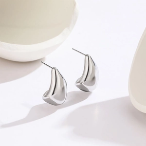 Minimalist silver teardrop earrings in polished titanium steel on white ceramic background