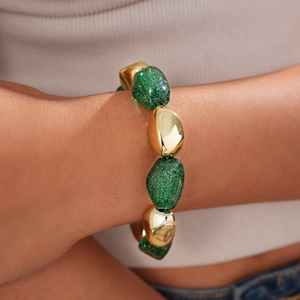 Detail of bohemian acrylic green glitter and gold metal beaded bracelet on woman wrist